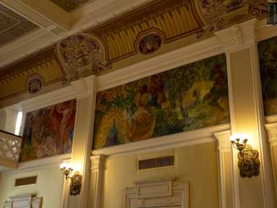 Le pareti grigie e ocra, scandite da porte e colonne, sono dipinte lungo tutto il perimetro da dieci scene allegoriche a tempera dei fratelli Mario e Guido Prayer